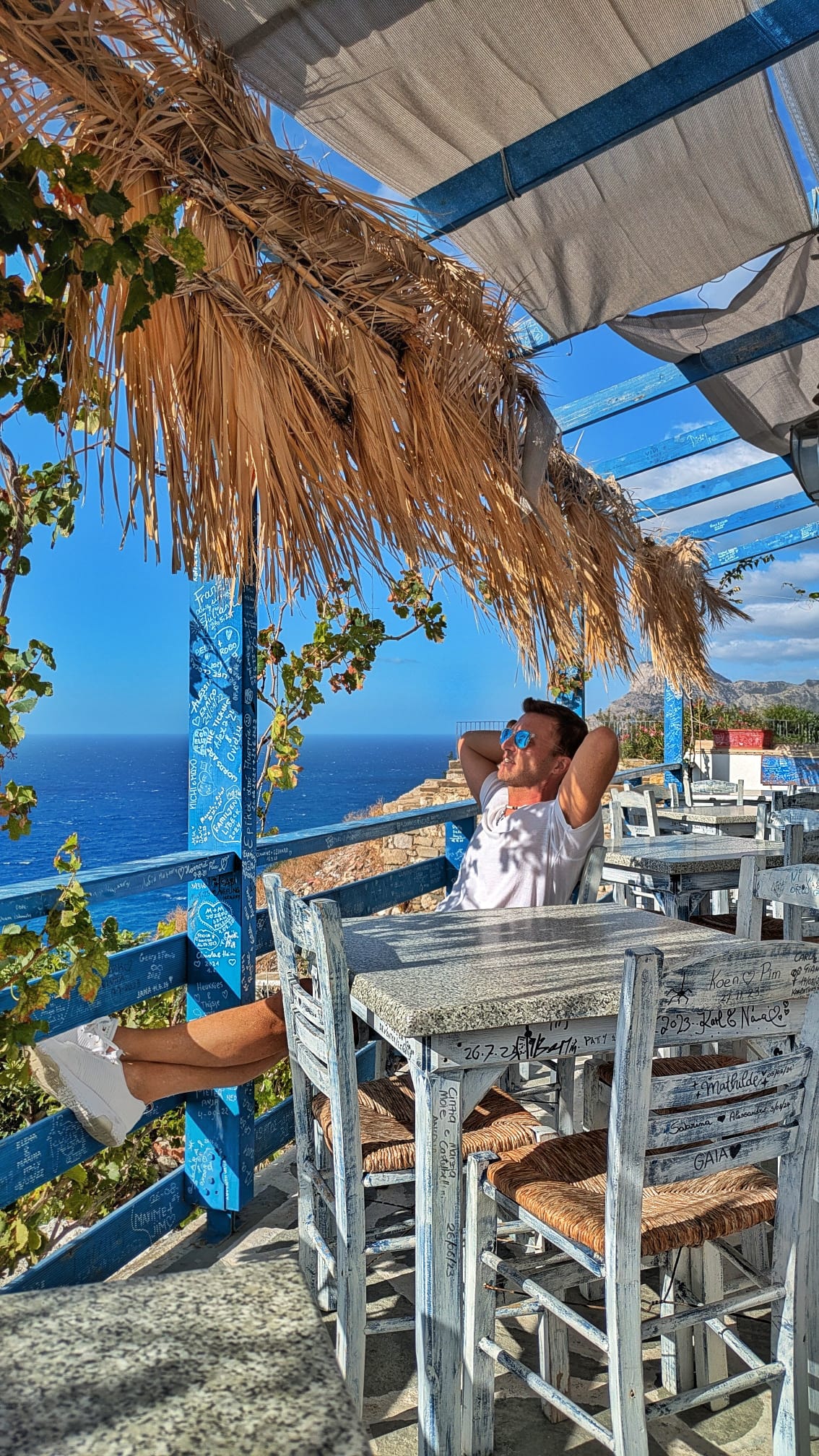 Alessandro Di Martino seduto su una terrazza con vista sul mare di Karpathos